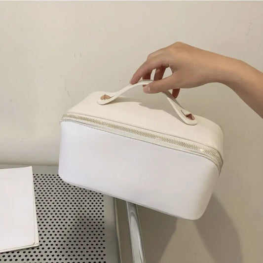 Trousse de toilette  Voyage en cuir  blanc dans une main de femme - La trousse Beauté